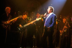 Gilbert Bécaud chantant et maintenant lors d'un concert